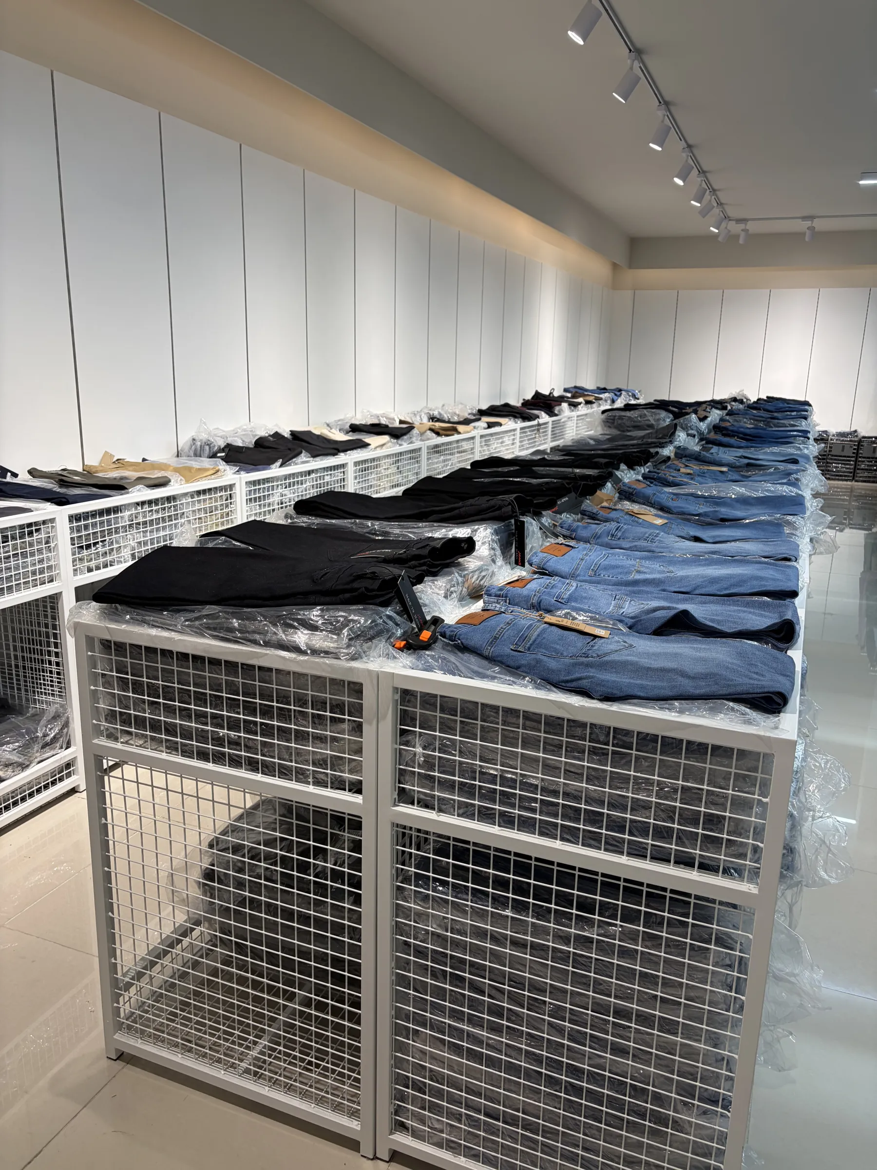 Armazém da HUANG'S LUA CINTILANTE: calças de ganga em caixas de rede ao longo do corredor