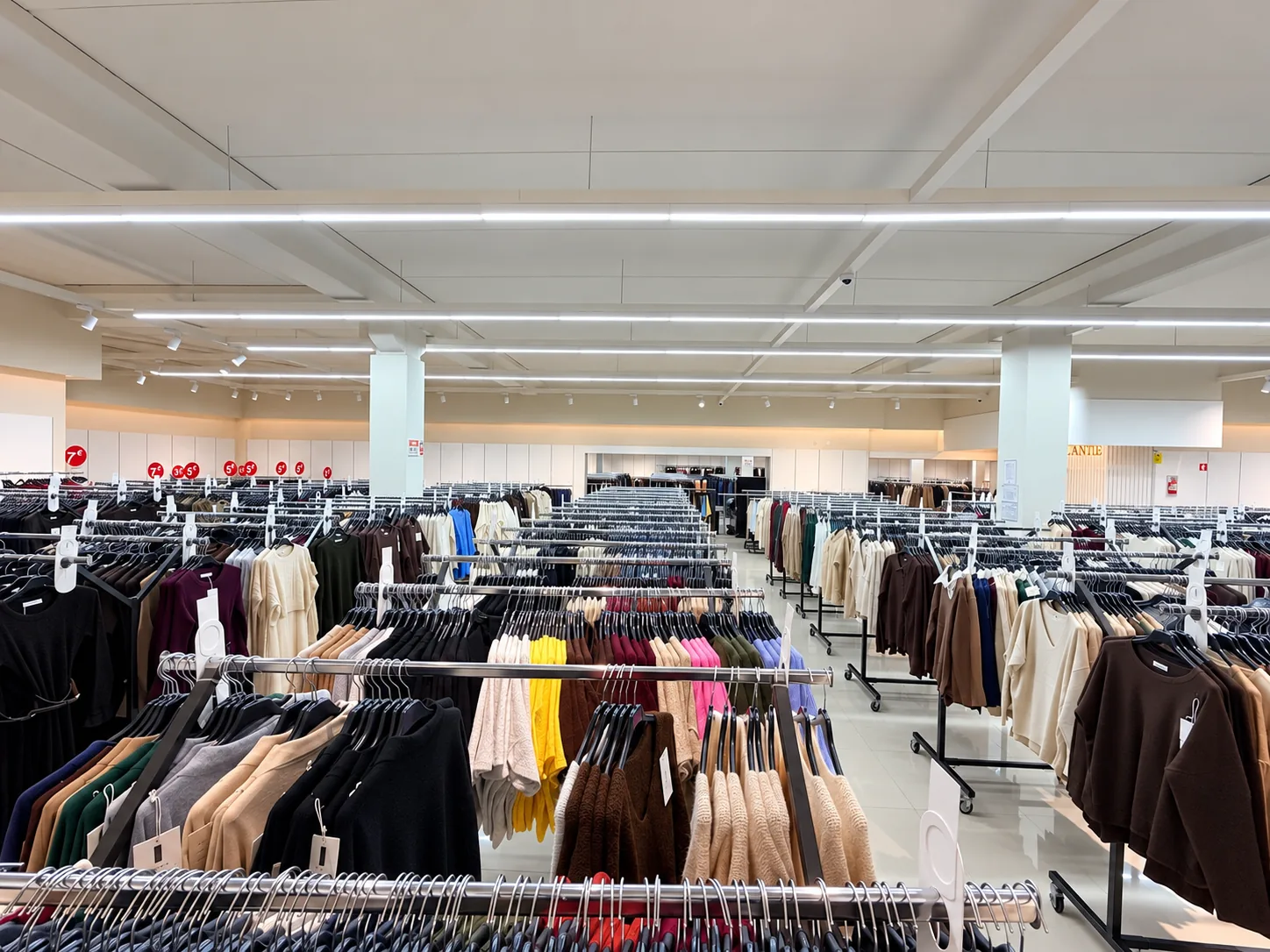 Vista panorâmica do interior da loja HUANG'S LUA CINTILANTE em Árvore: corredores de araras com malhas e moda feminina